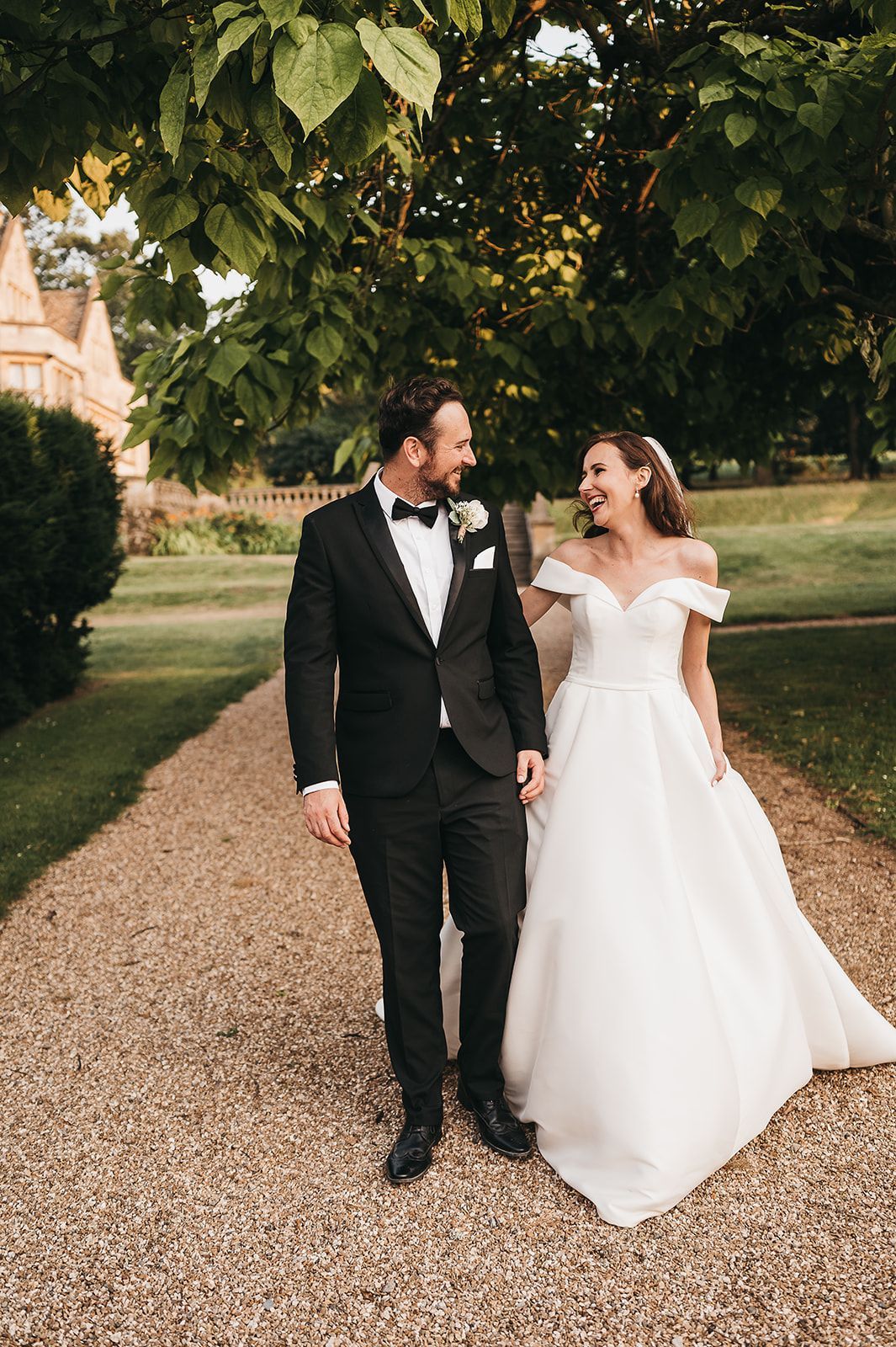 A bride and groom are walking down a gravel path.