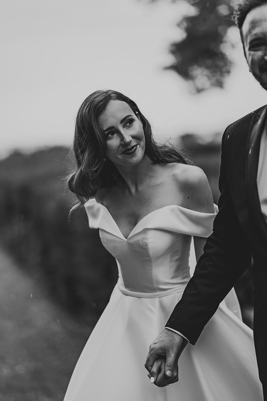 A black and white photo of a bride and groom holding hands.
