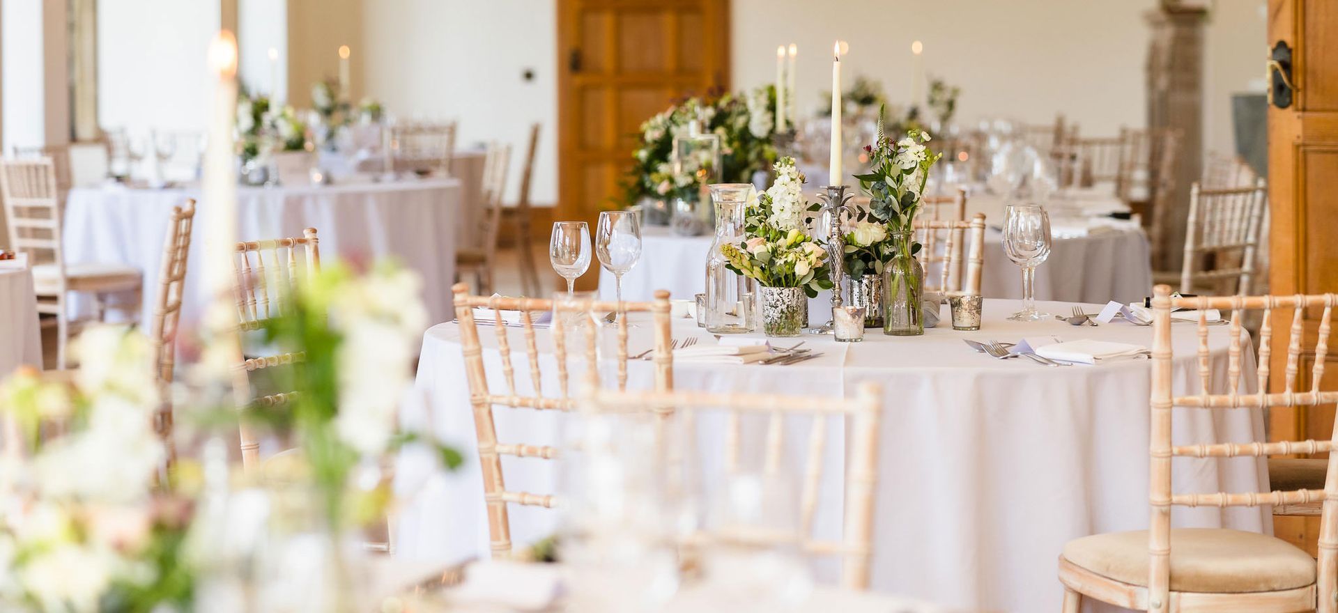 A room filled with tables and chairs set up for a wedding reception.