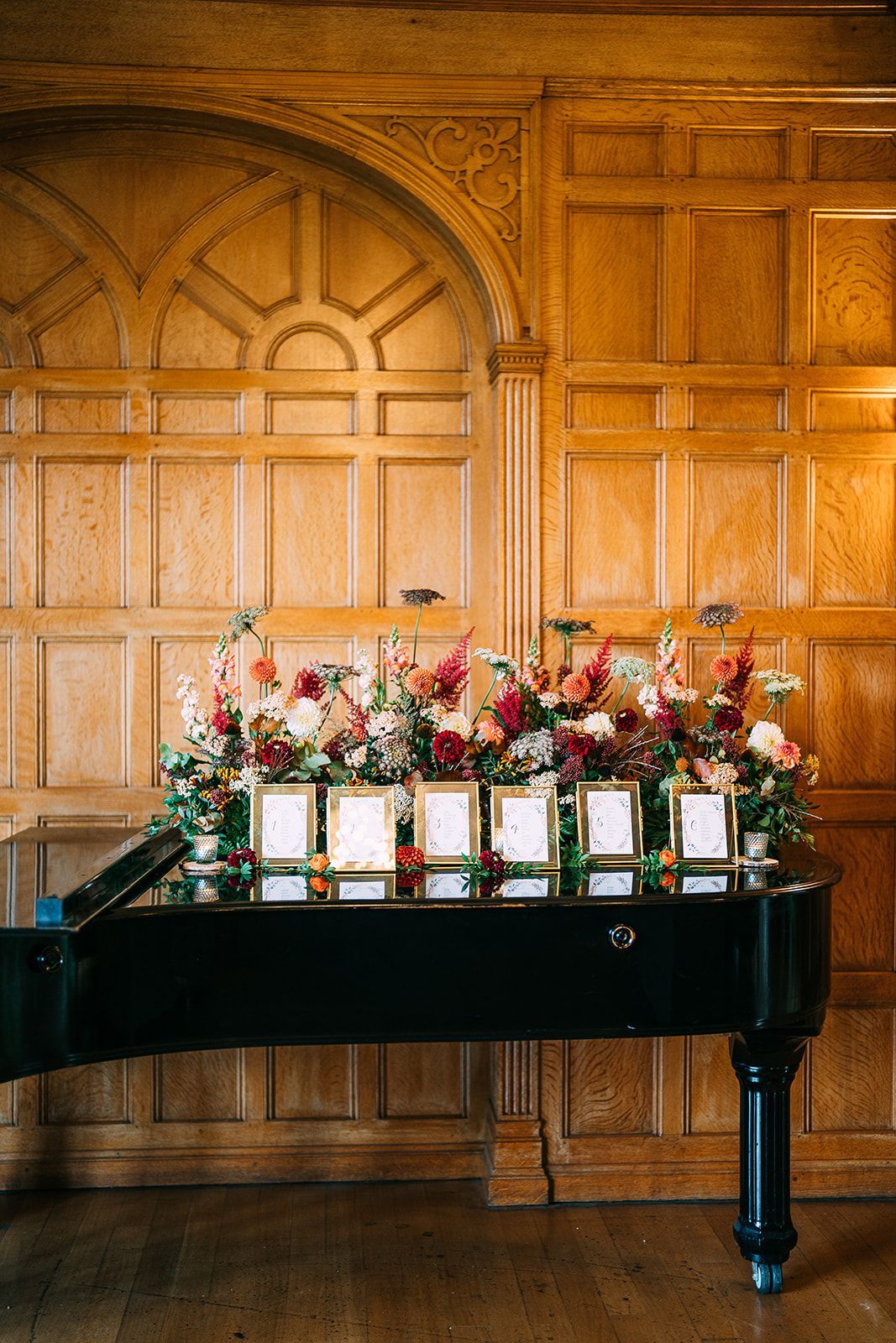 A piano is sitting in front of a wooden wall with flowers on it.