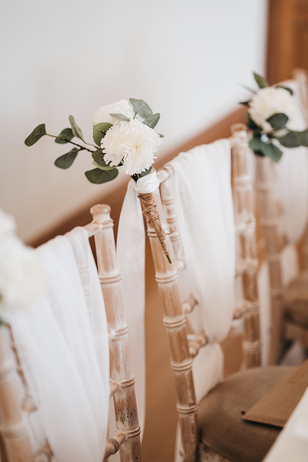 A row of chairs decorated with white flowers and greenery.