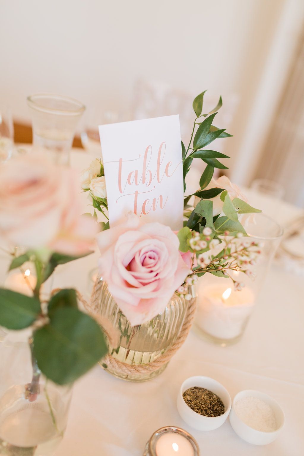A table setting with flowers , candles , and a table number.