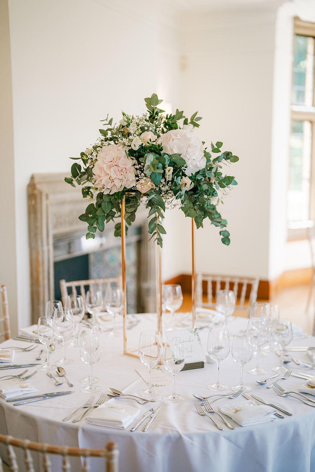 A table set for a wedding reception with a vase of flowers on it.