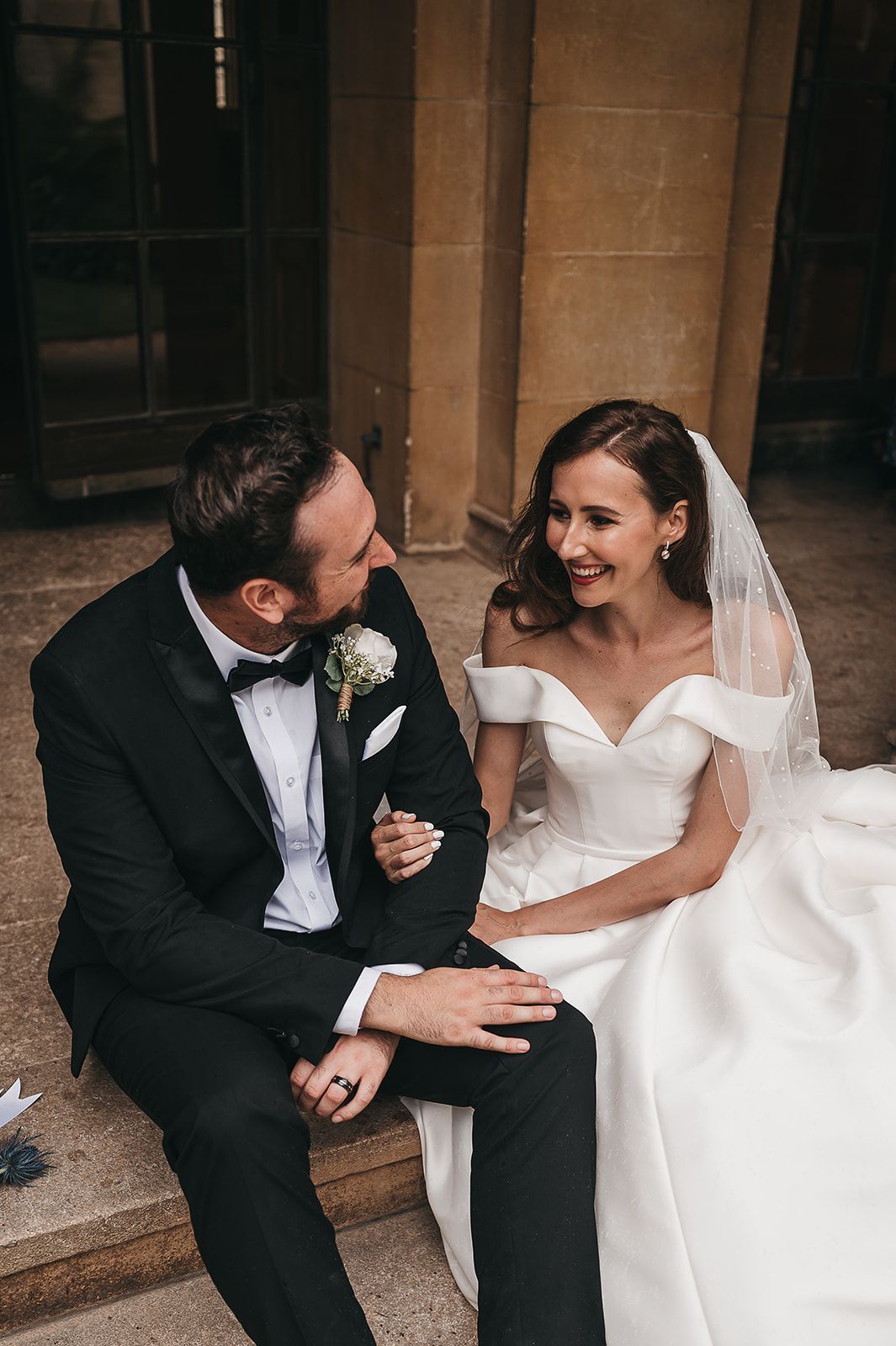 A bride and groom are sitting on the steps of a building.