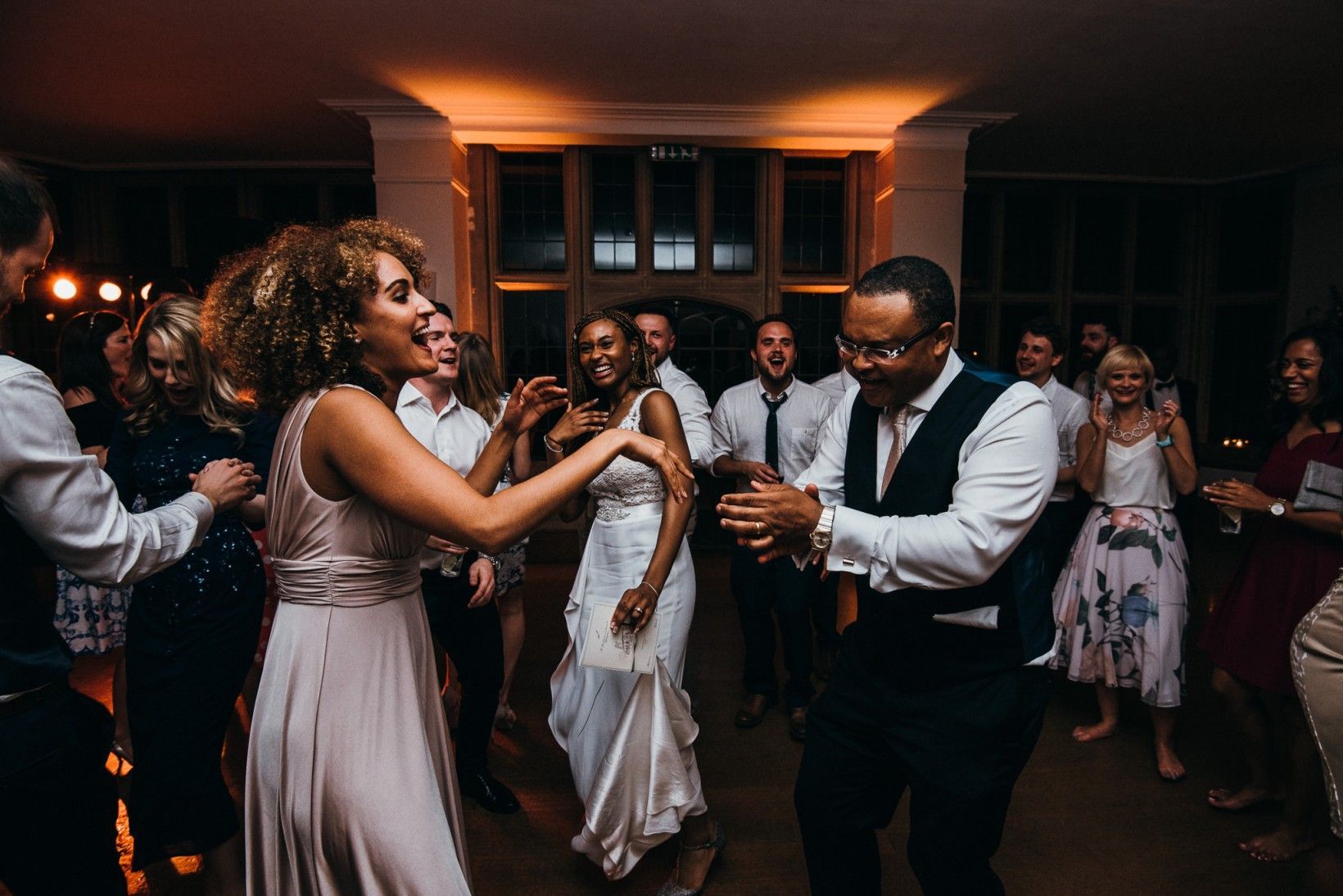 A bride and groom are dancing with their wedding guests at their wedding reception.