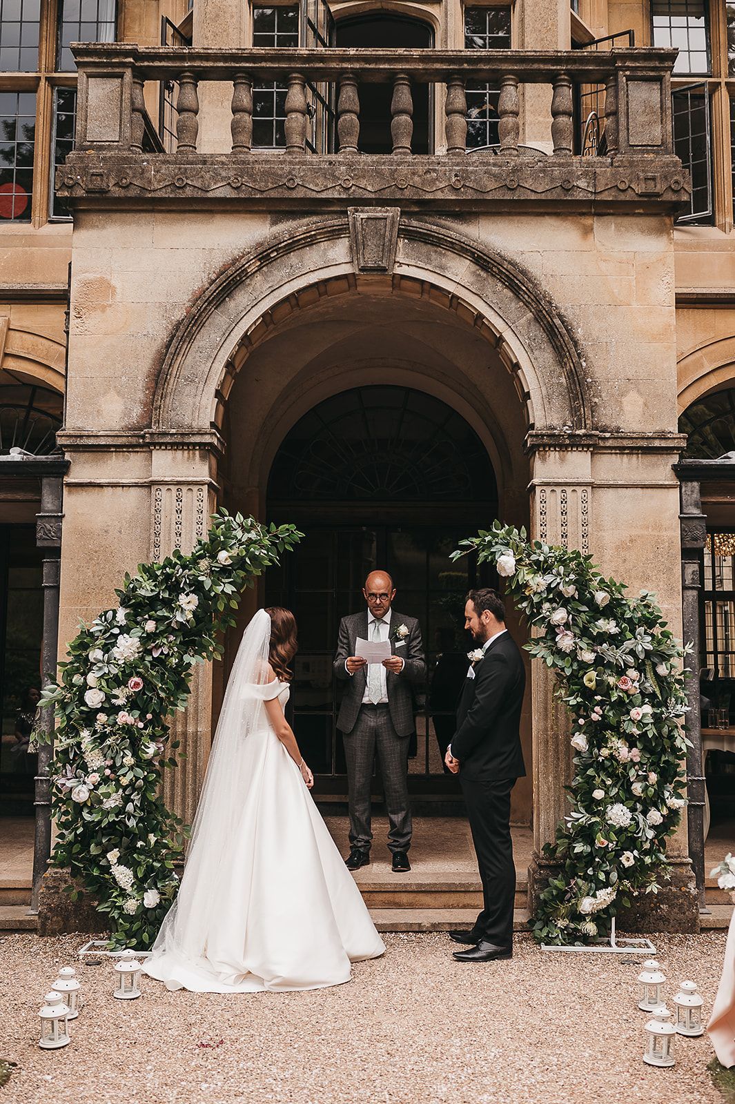 A bride and groom are standing in front of a building during their wedding ceremony.