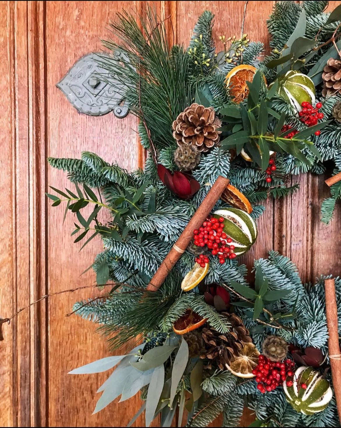 A christmas wreath is hanging on a wooden door.