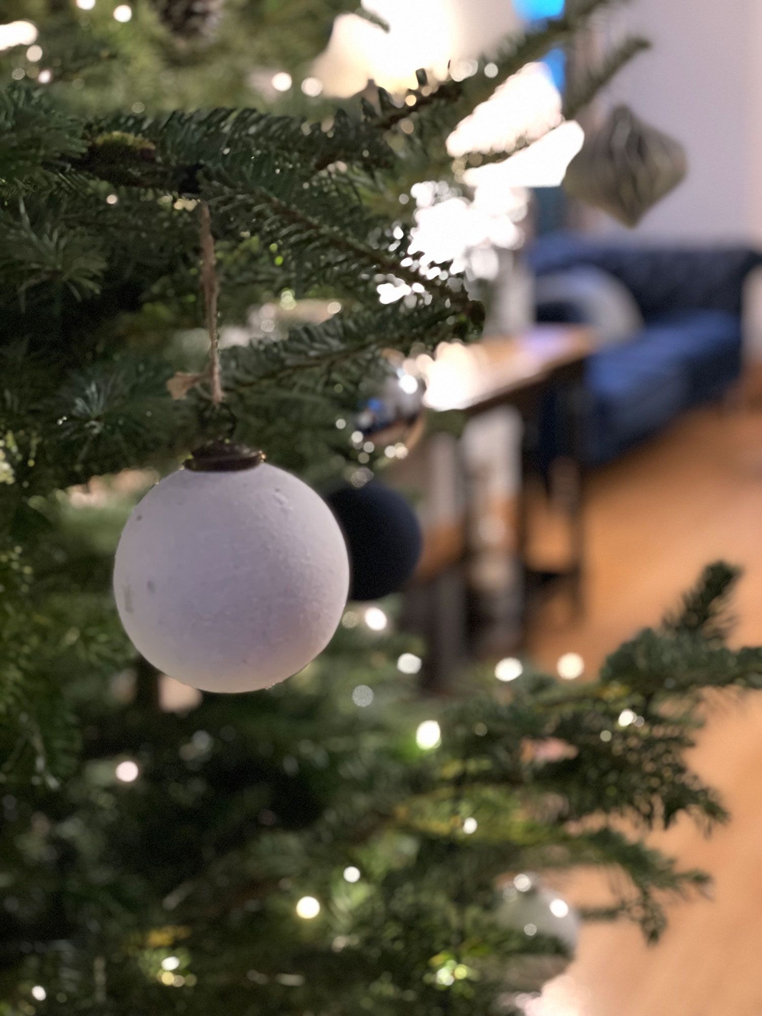 A christmas tree with a white ornament hanging from it