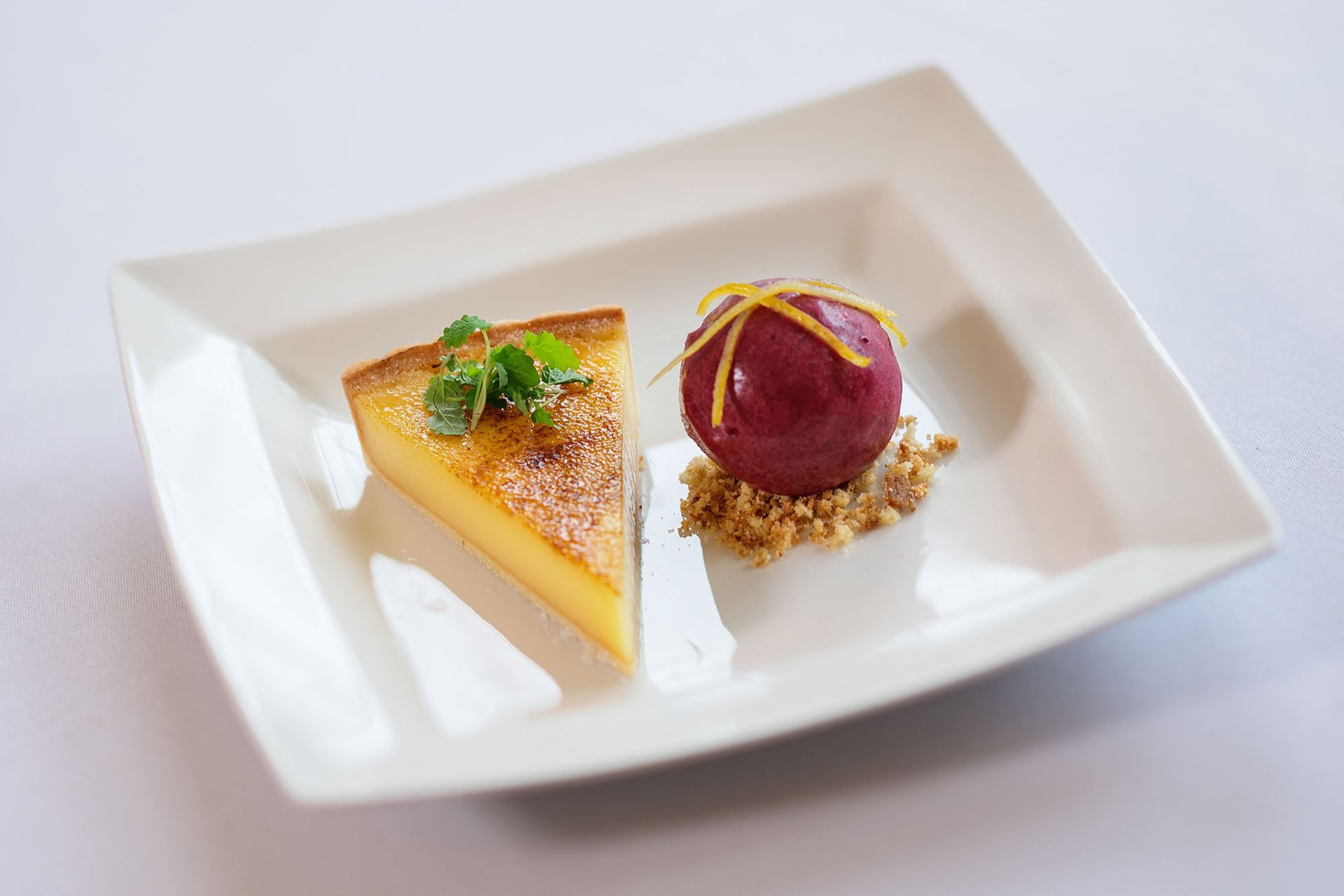 A white plate topped with a slice of pie and a purple dessert.
