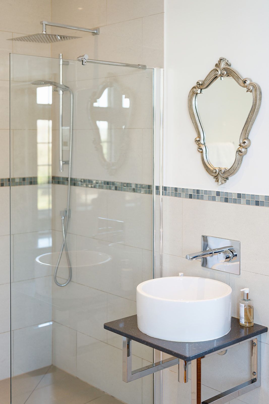 A bathroom with a sink , shower , and mirror.