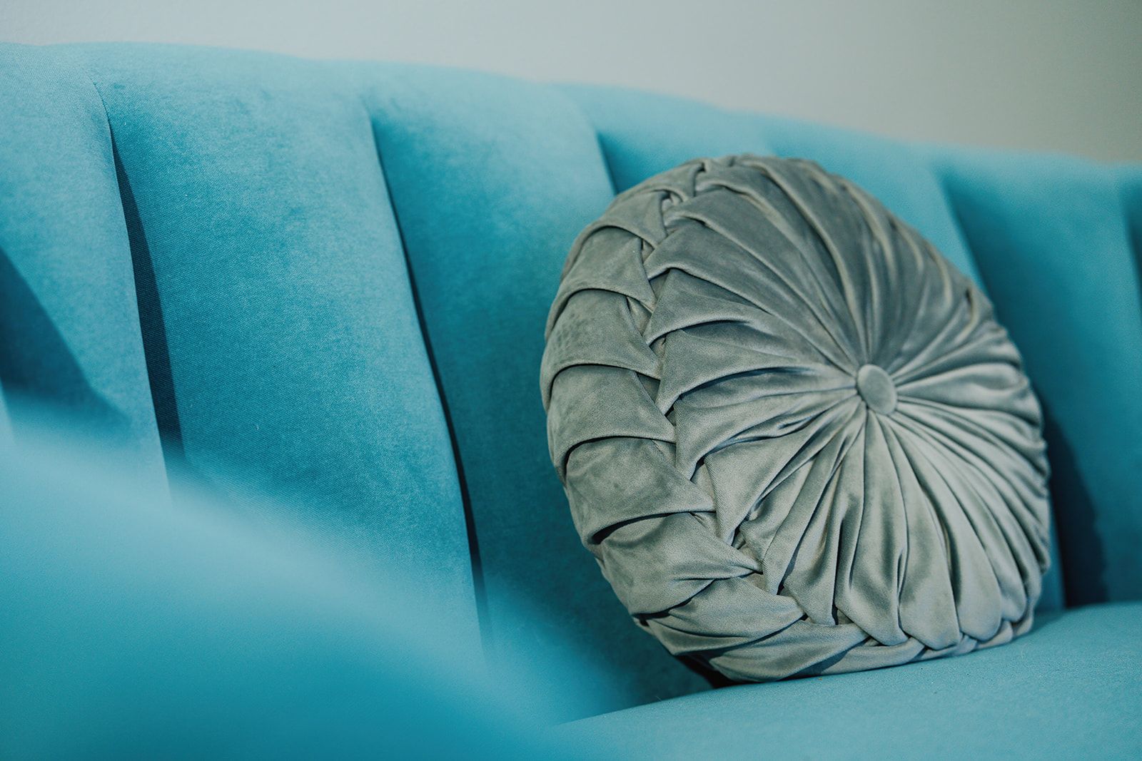 A round pillow is sitting on a blue couch.