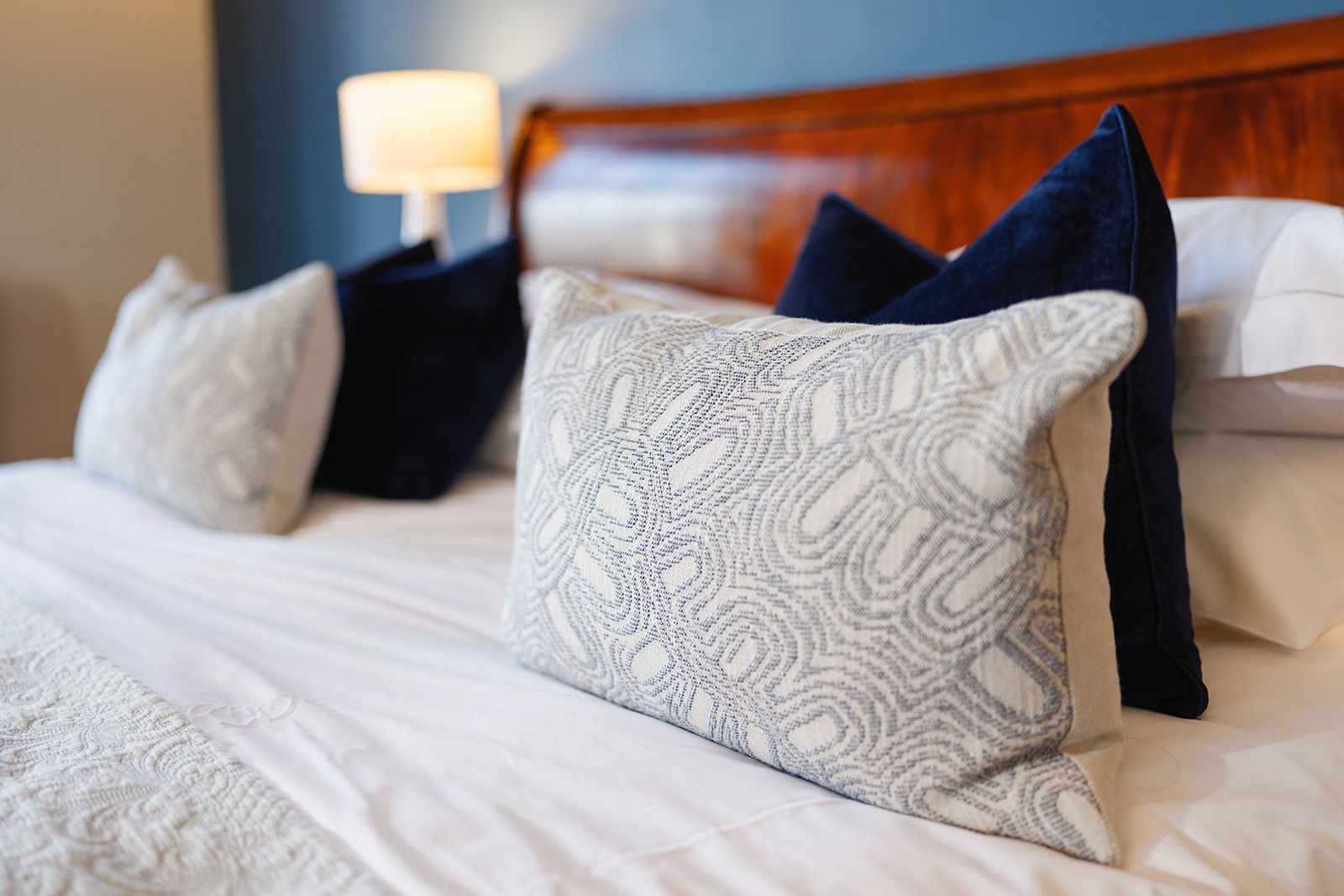 A bed with white sheets and blue pillows on it.