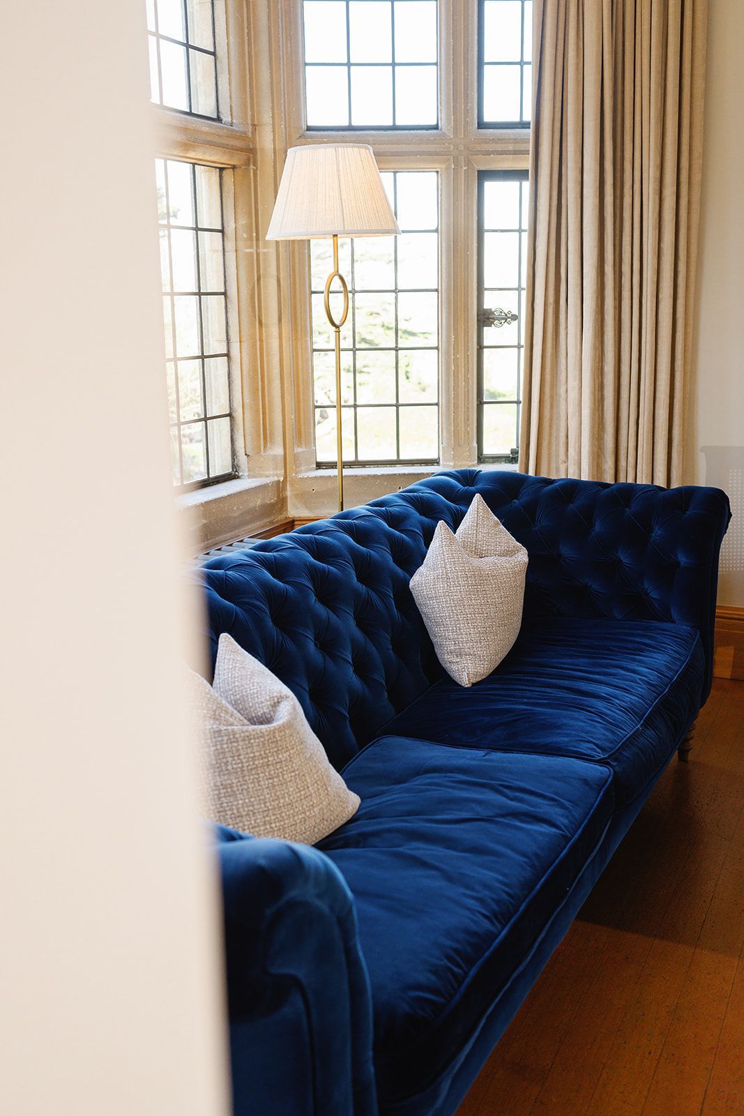 A blue couch is sitting in front of a window in a living room.