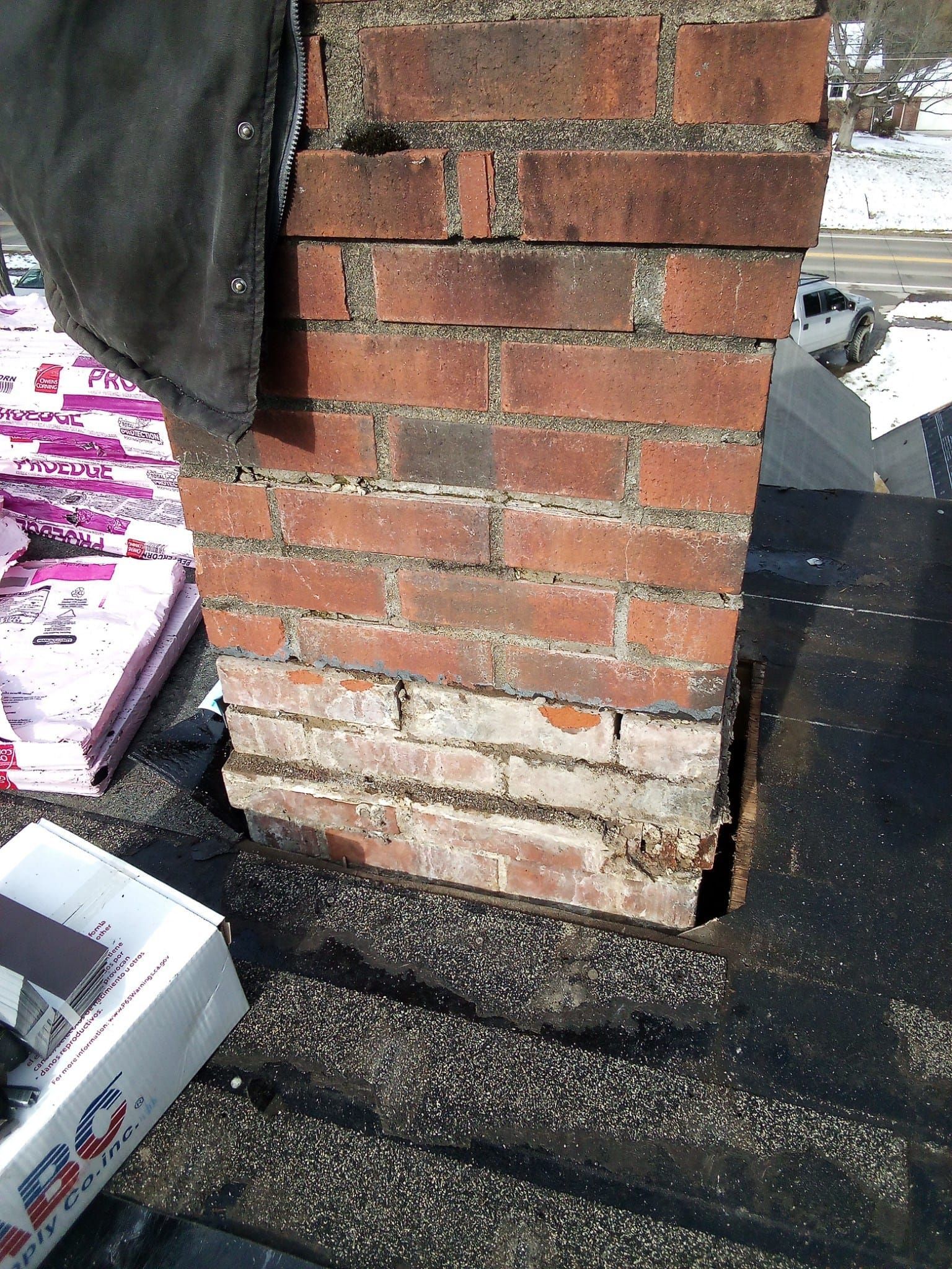 A brick chimney is sitting on top of a roof next to a box of pizza.