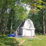 A group of people are working on the roof of a barn.