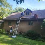 Two men are working on the roof of a house.