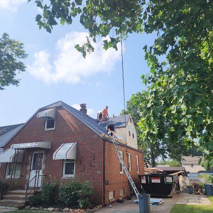 A man is standing on the roof of a brick house.