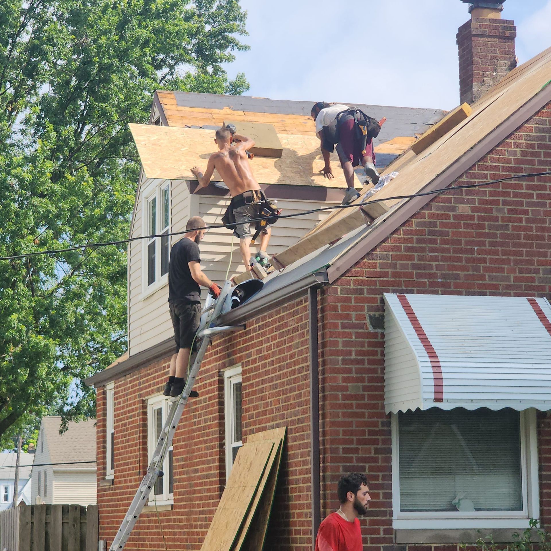 A group of men are working on the roof of a brick house