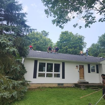 A group of people are working on the roof of a house.