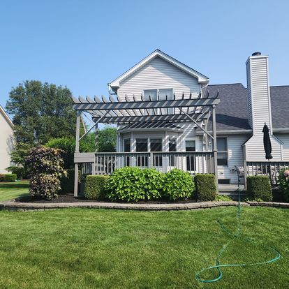 A house with a pergola and a hose in front of it