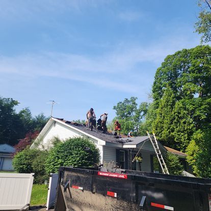 A group of people are working on the roof of a house.