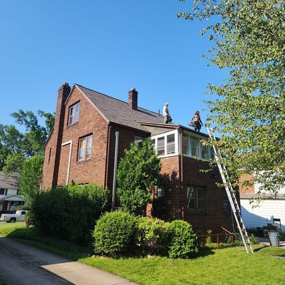 Two men are working on the roof of a brick house