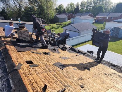 A group of men are working on the roof of a house.