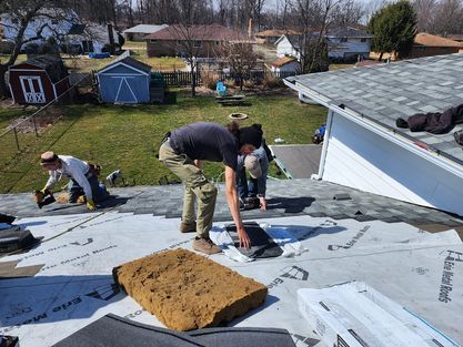 A group of people are working on a roof of a house.