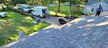A man is standing on top of a roof next to a truck.
