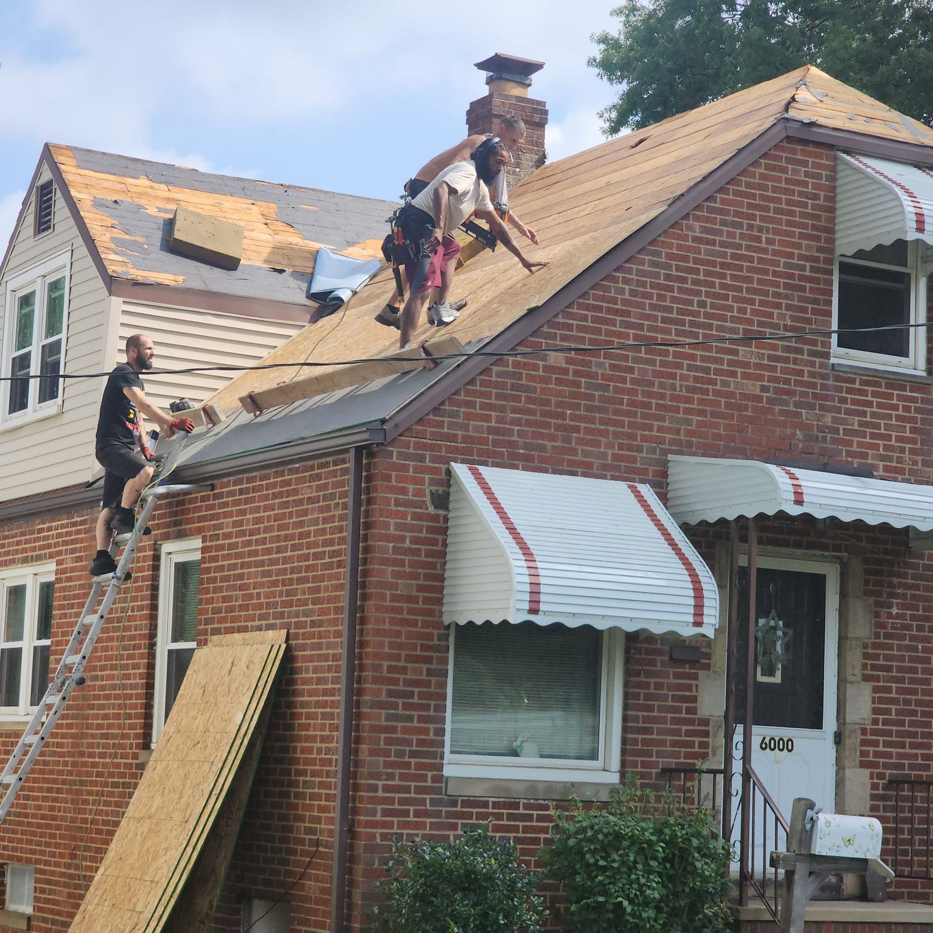 A group of people are working on the roof of a brick house