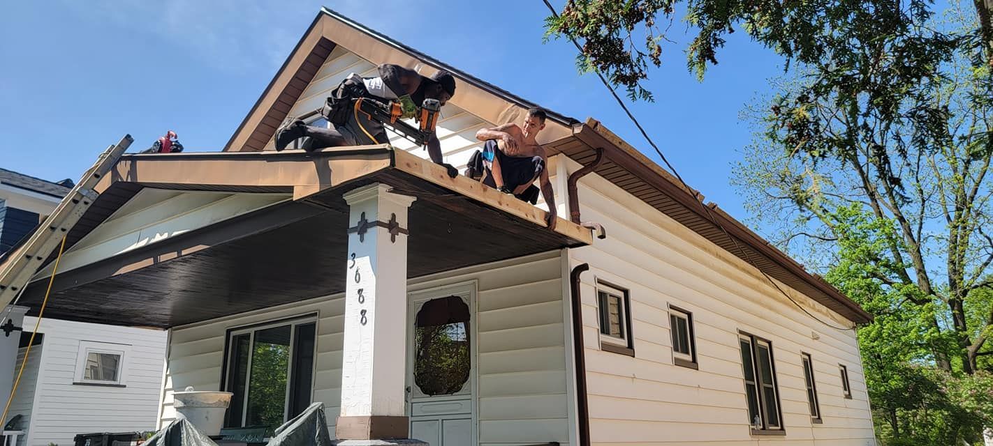 A group of men are working on the roof of a house.