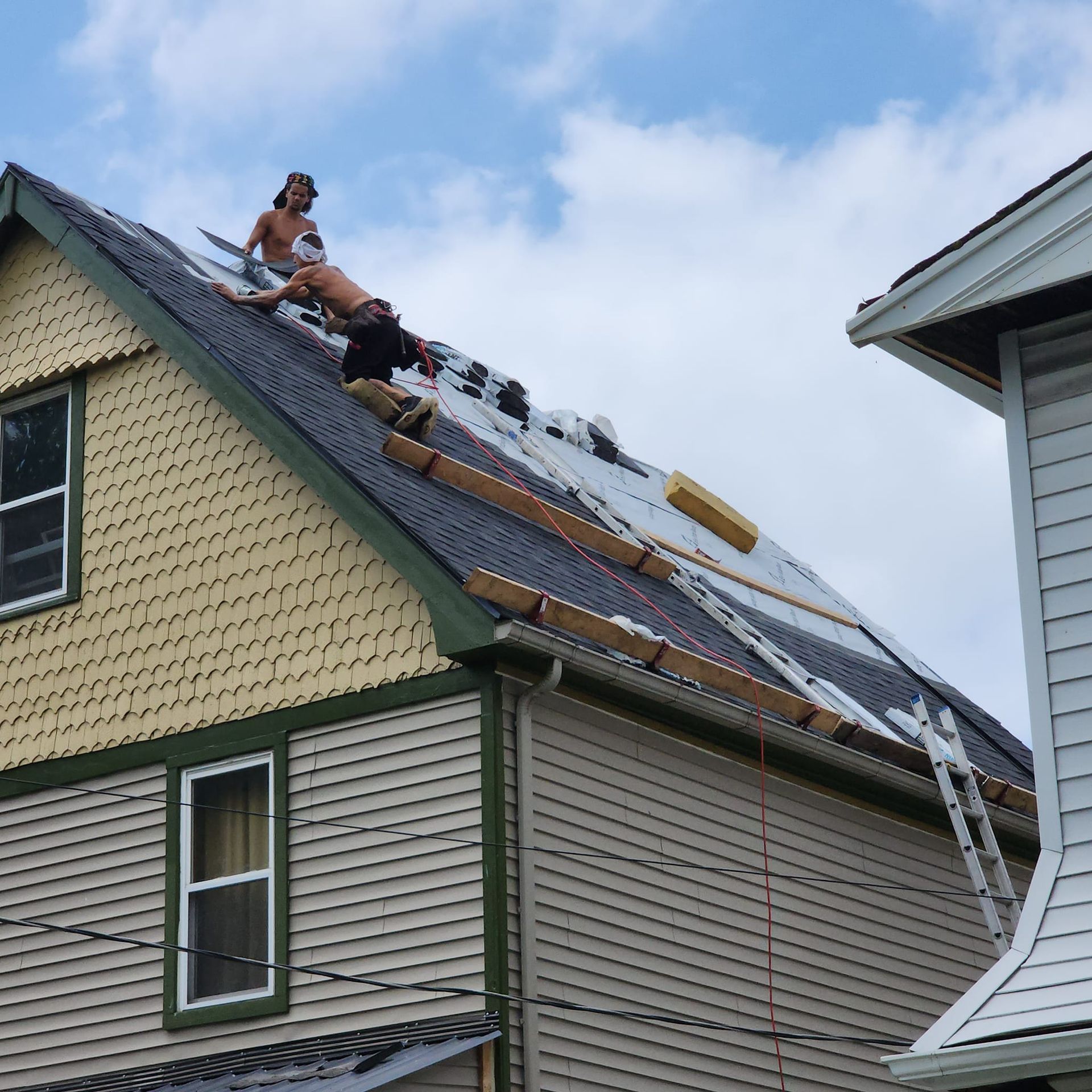 Two men are working on the roof of a house