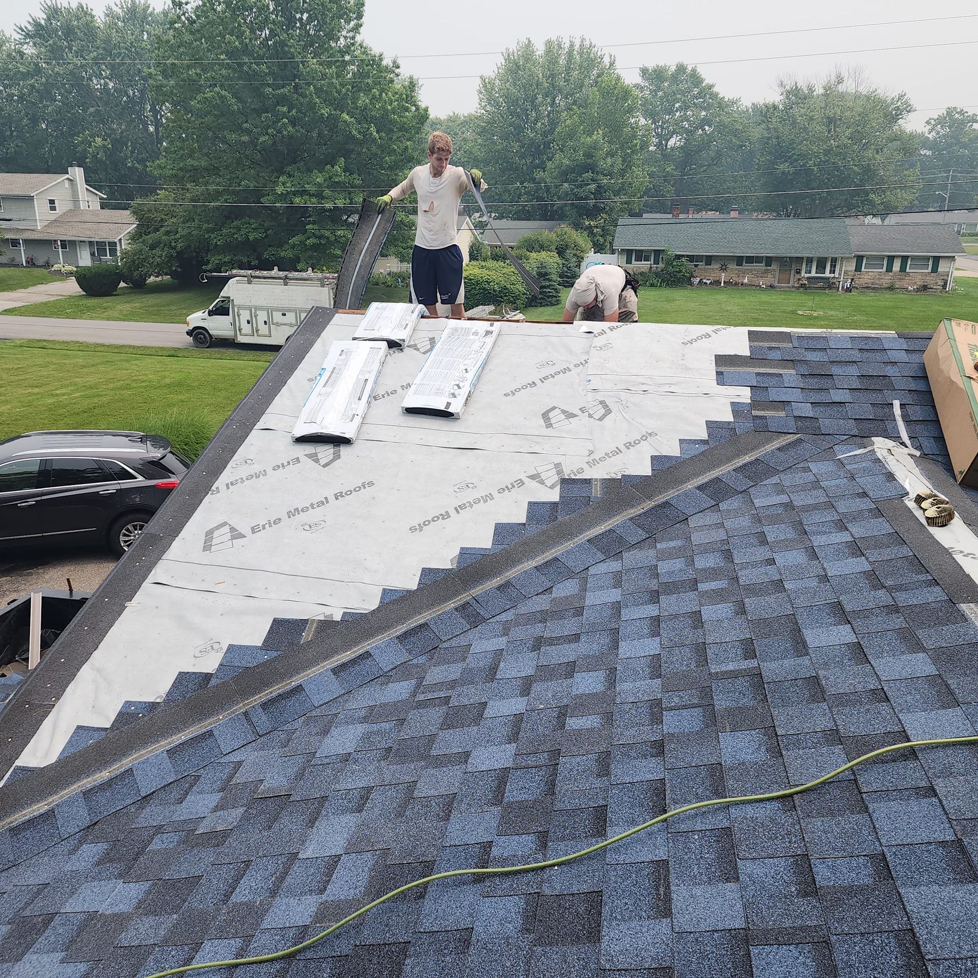 A man is standing on top of a blue roof.