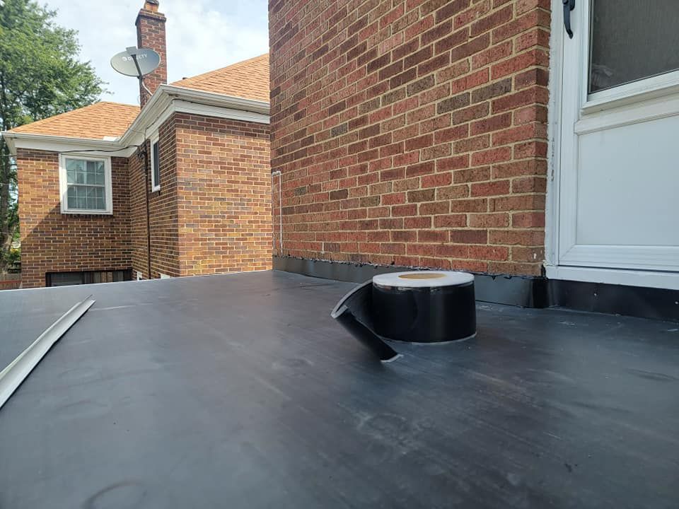 A roll of black tape is sitting on the ground in front of a brick building.