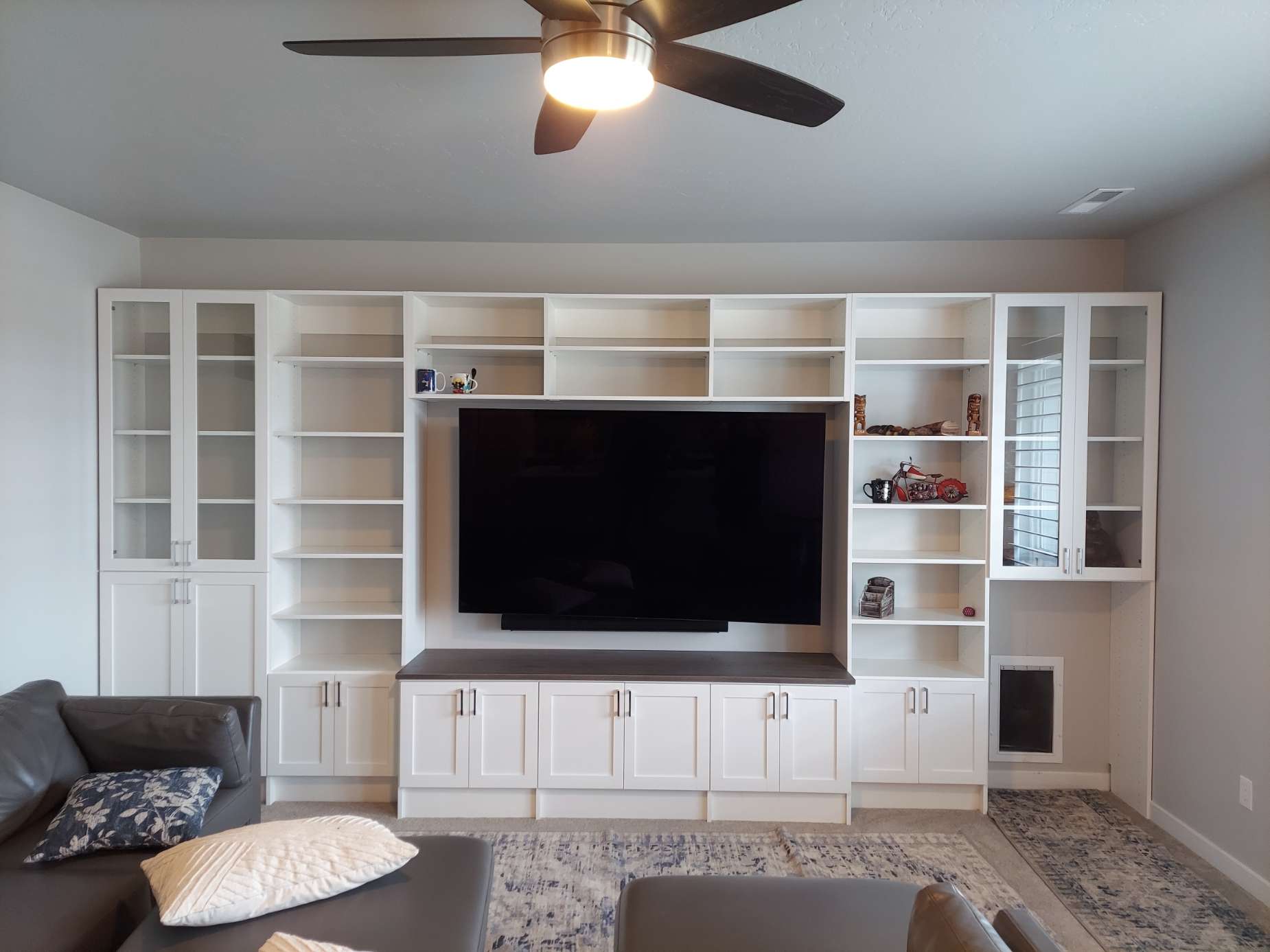 A living room with a ceiling fan and a flat screen tv