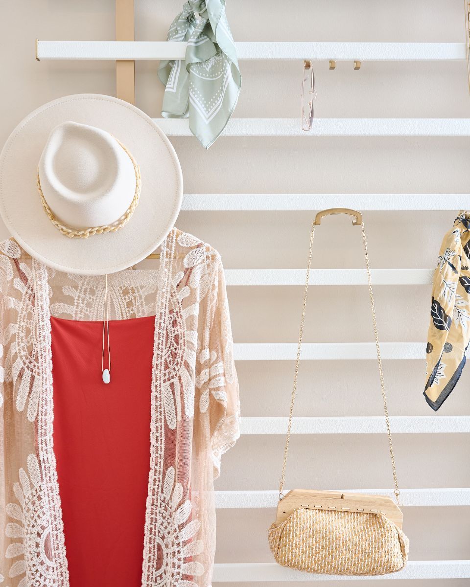 A hat and a red dress are hanging on a rack.