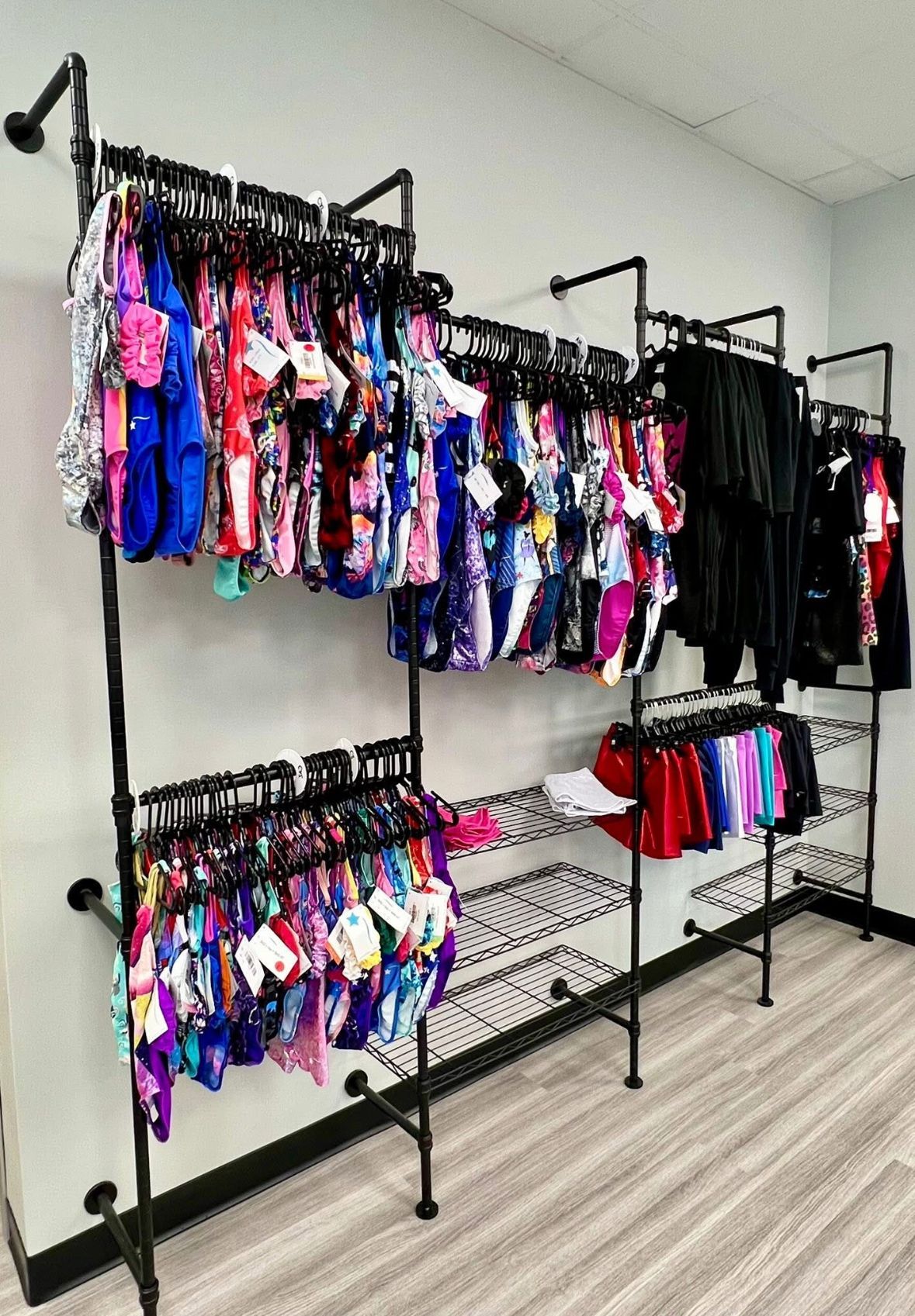 Gymnast with arms outstretched, wearing black and pink leotard, indoors.