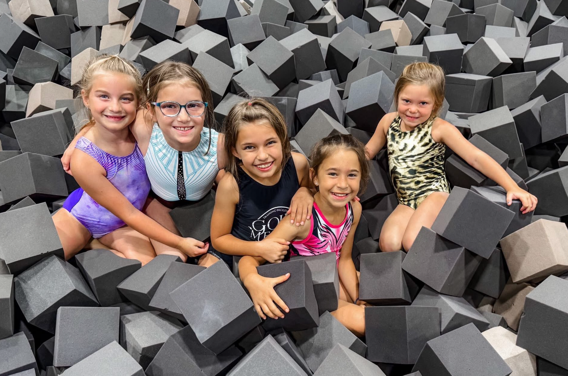 Girls in colorful shirts hanging from wooden wall bars.