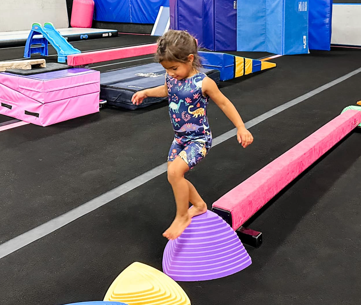 Boy flexing arms, wearing a medal, white tank top, and wristbands against a purple background.