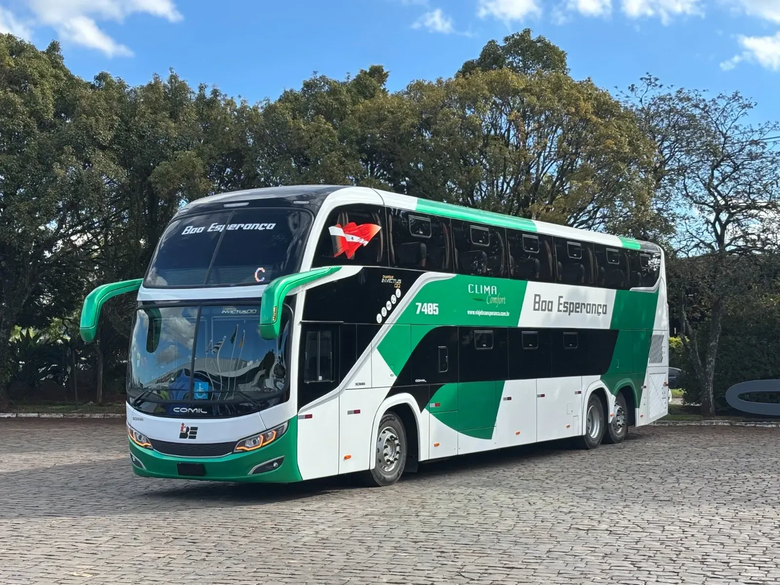 Um ônibus verde e branco está estacionado em uma estrada de paralelepípedos.