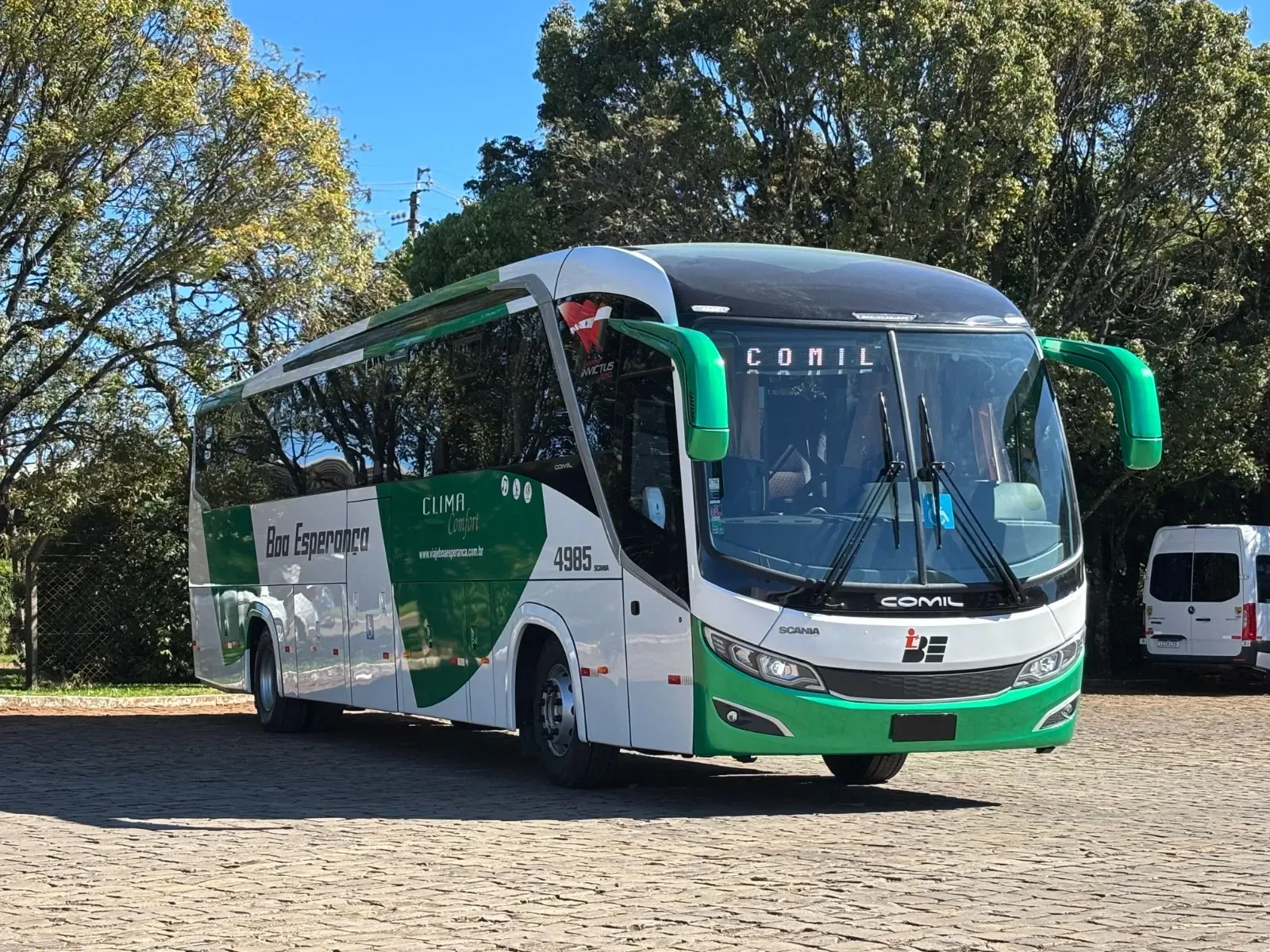 Um ônibus verde e branco está estacionado em uma estrada de cascalho.