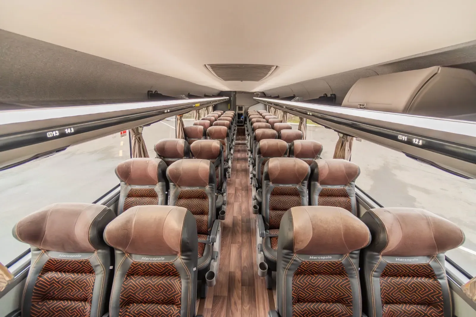 O interior de um ônibus com fileiras de assentos e piso de madeira.