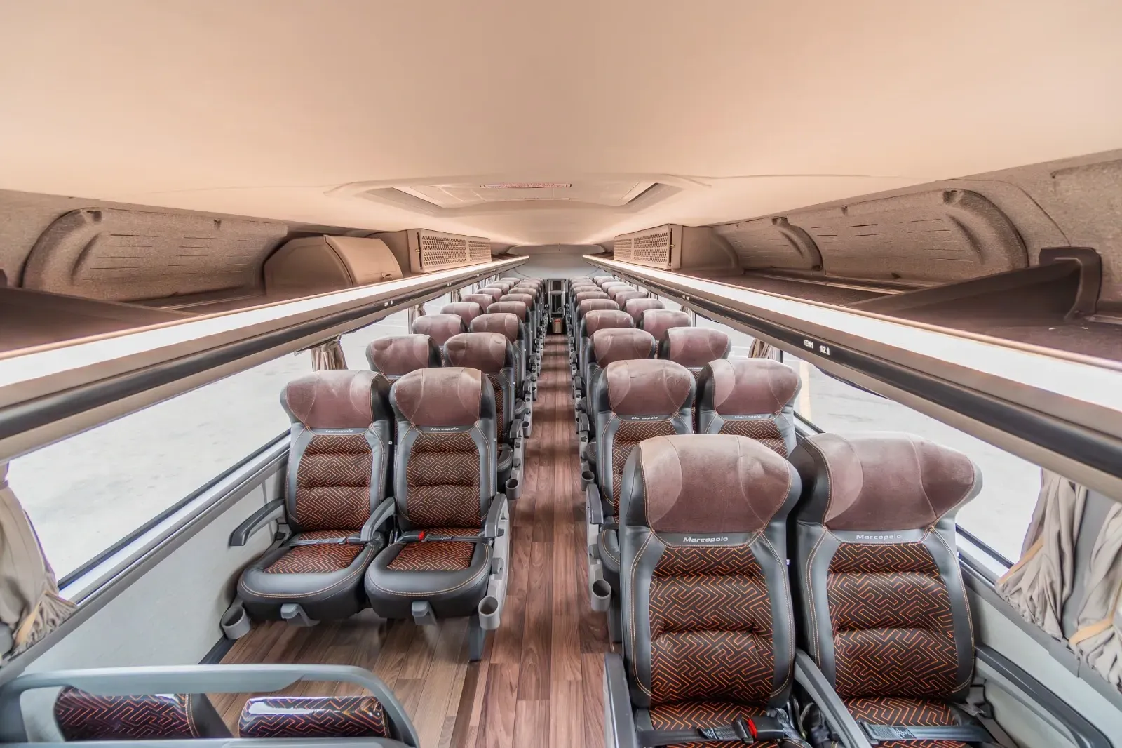 O interior de um ônibus com fileiras de assentos e piso de madeira.