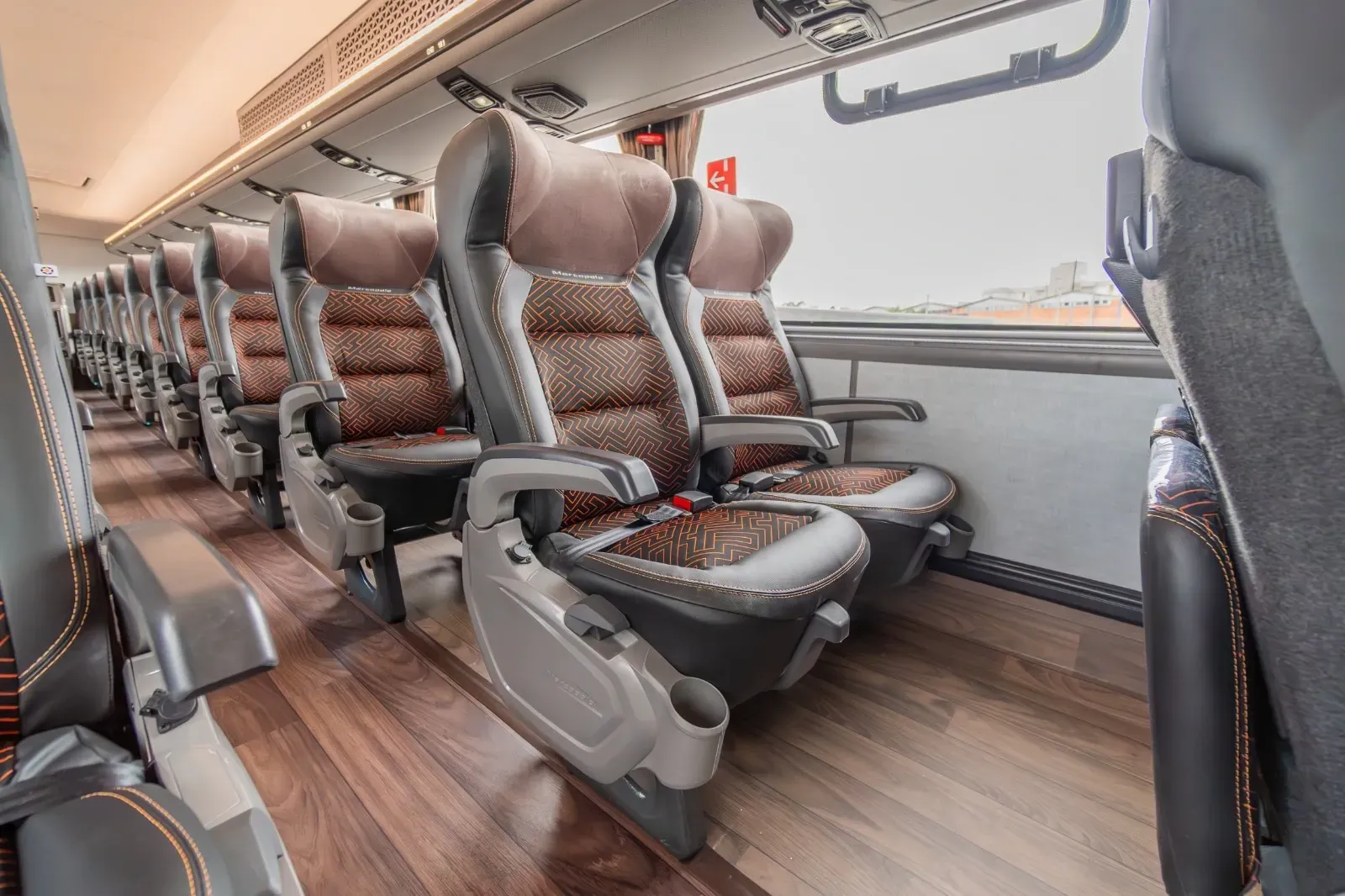 Uma fileira de assentos em um ônibus com piso de madeira.