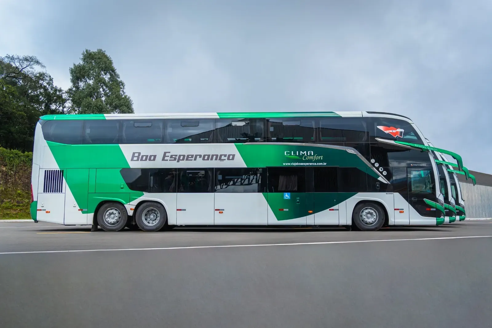 Um ônibus de dois andares verde e branco está estacionado na beira da estrada.