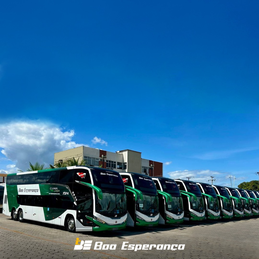 Fila de ônibus de dois andares, verde e branco, estacionados sob um céu azul brilhante. Logotipo 