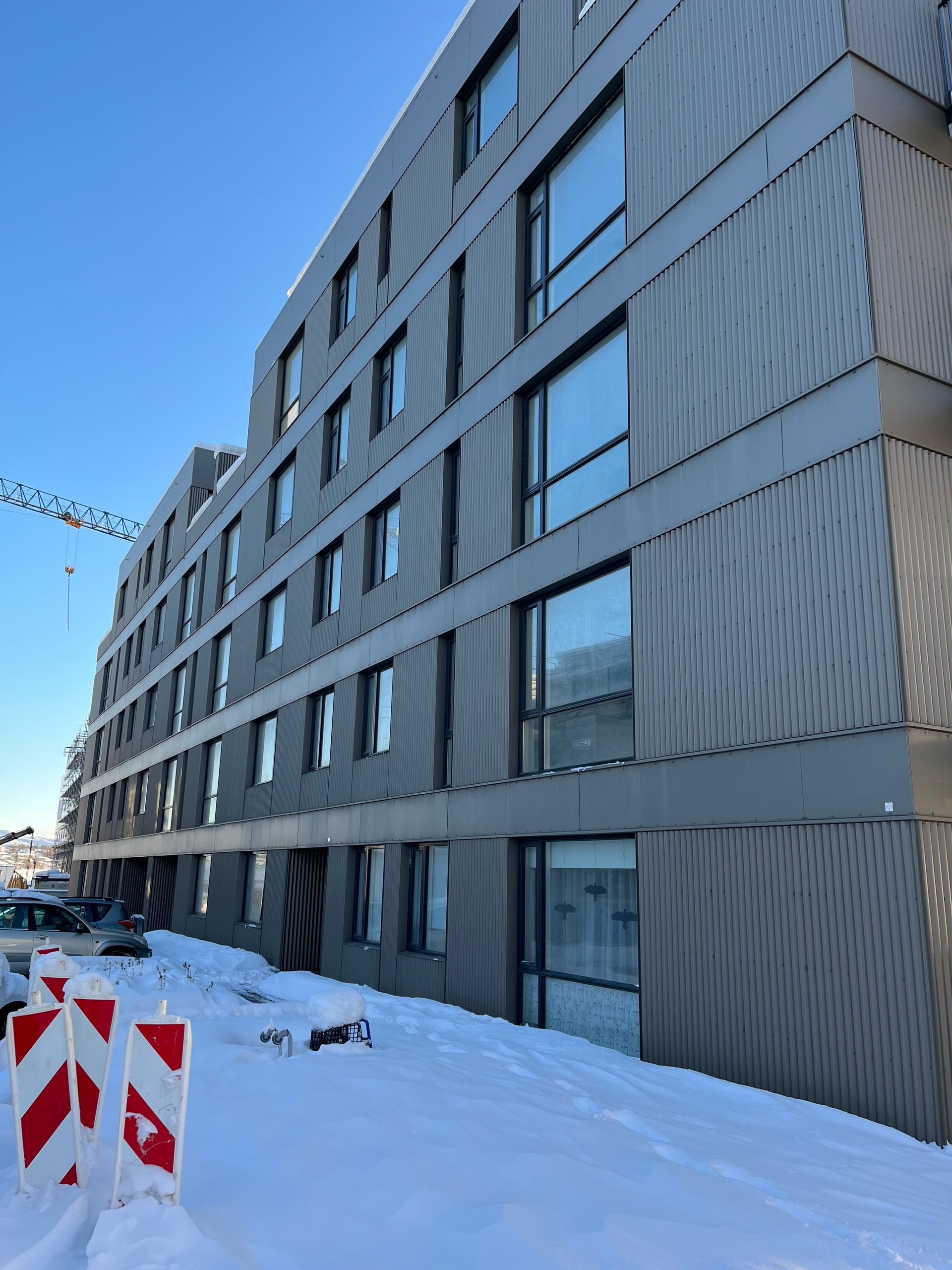 Svart-hvít mynd af byggingarlist á móti skýjuðum himni, sem sýnir skarpa horn og áferð.