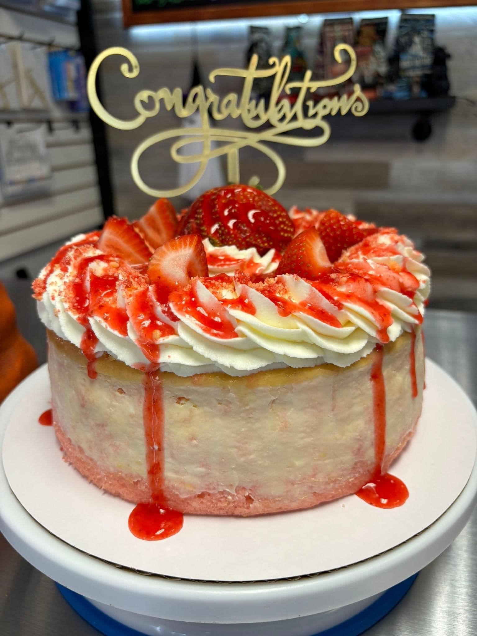A strawberry cheesecake with a congratulations cake topper on top of it.