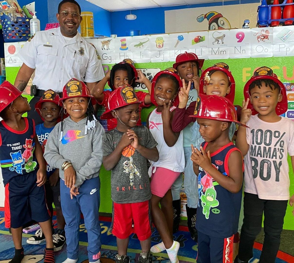A group of children wearing hard hats and a shirt that says 100 % mama 's boy