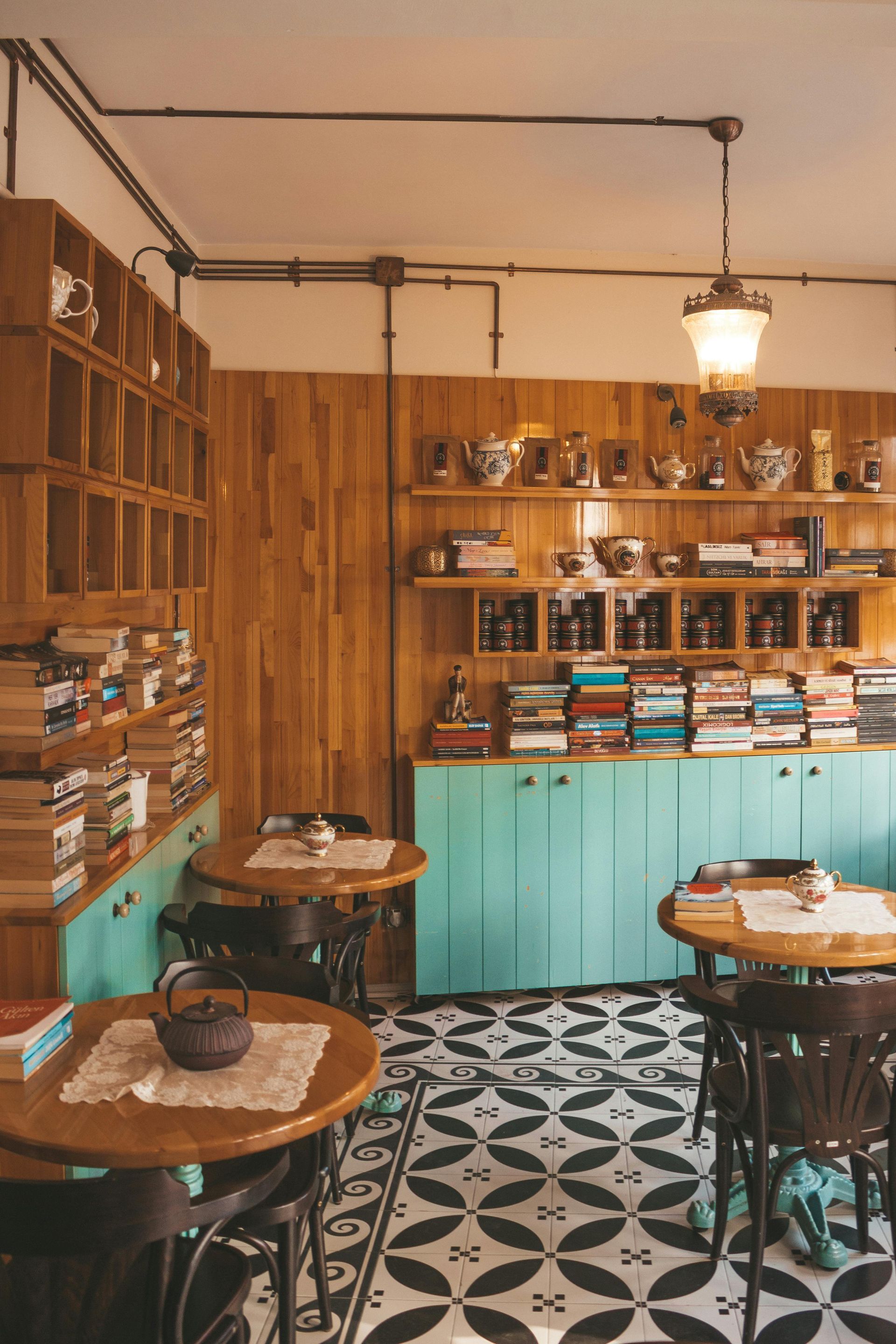 Een restaurant met tafels, stoelen en een theepot op tafel.